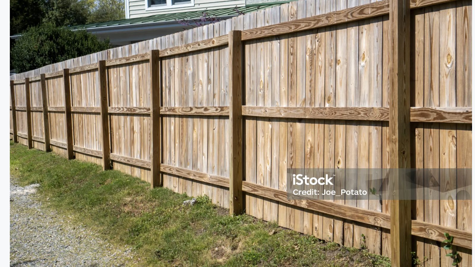 Wood fence installed with posts and horizontal rails facing outward toward the street