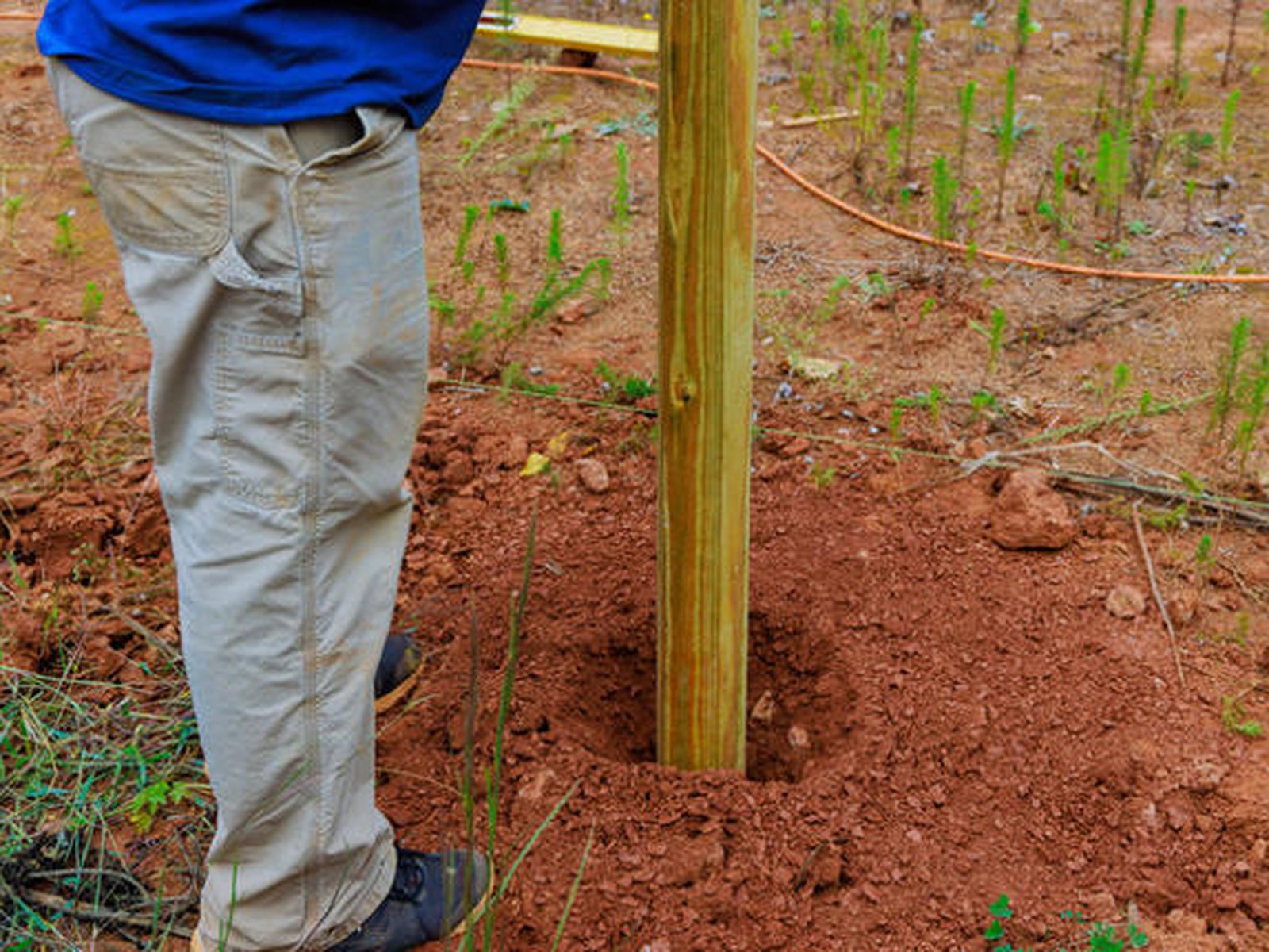 Fence post standing in an open hole before concrete is poured